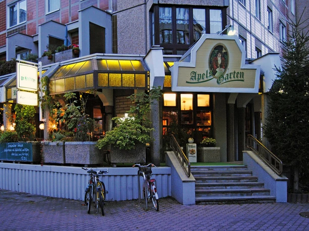 Pohled na vchod do restaurace Apels Garten s venkovním posezením před ní za soumraku, Gastronomie v Lipsku, Pivní zahrádka, Kulinářské speciality