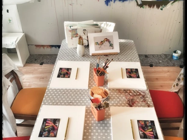 Kreativer Maltisch im Atelier Klexx - Freizeitaktivitäten in der Leipzig Region Großer Tisch mit viel Stühlen, auf dem sämtliche Malutensilien liegen. Im Atelier Klexx kann man mit Leinwänden, bunten Farben und Pinseln kreativ werden und seiner Fantasie Raum geben, Freizeit, Malen, Spaß, Kreativität, Familie, Leipzig mit Kindern