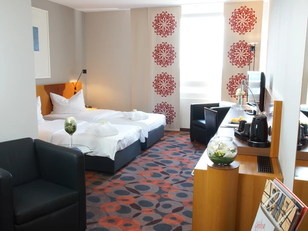 Pokoje Deluxe v hotelu Atlanta - Ubytování v Lipsku Pohled do interiéru hotelového pokoje s manželskou postelí, křeslem a dalším vybavením, ubytování, dovolená, krátkodobý pobyt