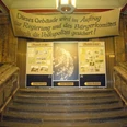 Treppenaufgang im Museum in der Runden Ecke - Friedliche Revolution in Leipzig Blick vom unteren Ende des Treppenaufgangs auf mehrere Banner und Poster, die auf das Museum in der Runden Ecke hindeuten, Friedliche Revolution, Geschichte, Freizeit, Sehenswürdigkeiten
