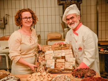 Bäckermeister der Bäckerei Kleinert Leipzig - Regionale Produkte aus Leipzig Eine Bäckerin und ein Bäcker der Bäckerei Kleinert halten einen Korb voller echter Leipziger Lerchen in der Backstube, Regionale Produkte aus Leipzig, Gastronomie, Kulinarik, Genuss