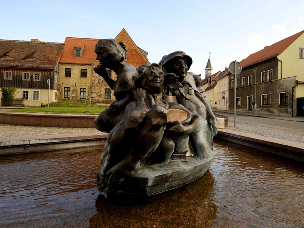 Schildbürgerdenkmal in Schildau ©W. Siesing Sackhupperbrunnen im Vordergrund und Häuserzeile am Markt in Schildau, Kultur, Sehenswürdigkeiten