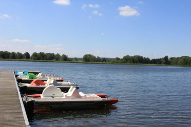 Widok na nadmorski kurort Schildau pod błękitnym niebem, rowery wodne zacumowane przy molo kąpielowym, przyroda, słońce, wycieczka