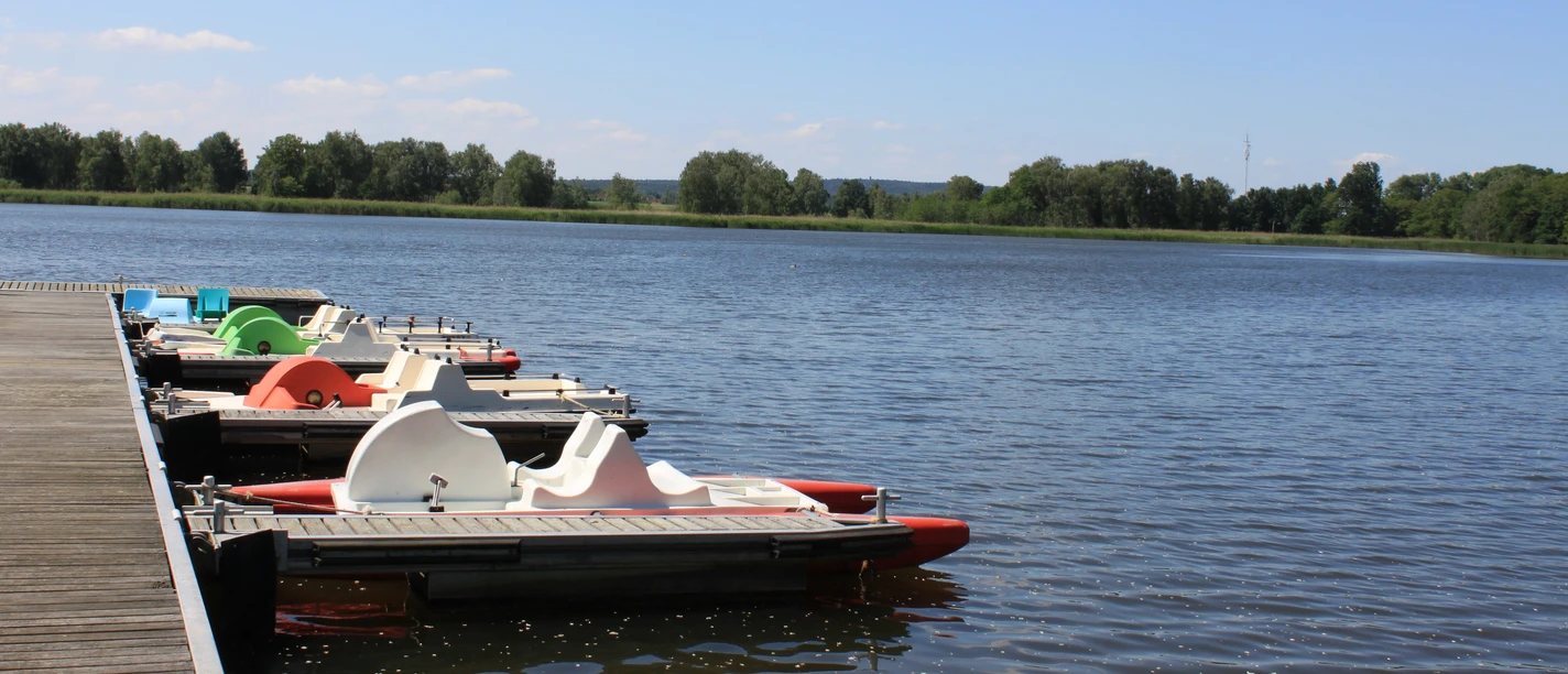 Widok na nadmorski kurort Schildau pod błękitnym niebem, rowery wodne zacumowane przy molo kąpielowym, przyroda, słońce, wycieczka