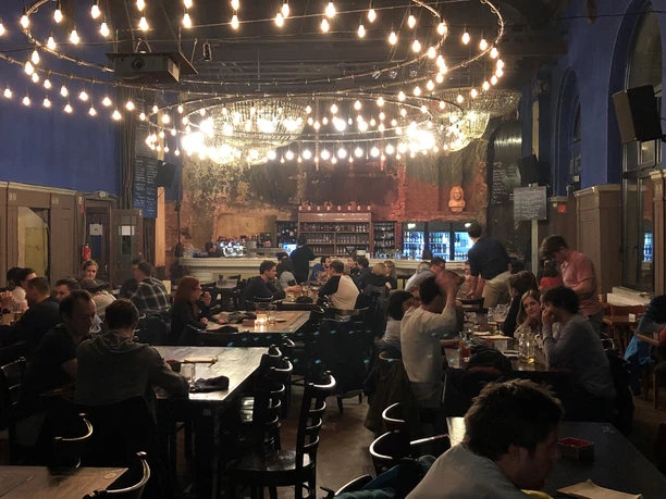 Cozy seating area with numerous guests at small tables, pub, gastronomy, leisure, event venue