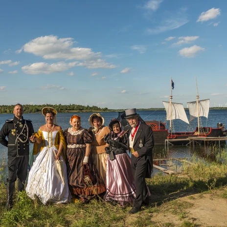 Am Biedermeierstrand stehen historisch kostümierte Darsteller vor Wasser mit einem kleinen Boot im Hintergrund, Veranstaltungen, Wasser