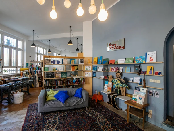 Pohled na barevný kreativní obchod Buchkinder Leipzig, jeho regály, výzdobu a posezení k posezení a čtení, kulturní centrum, kultura, volný čas.