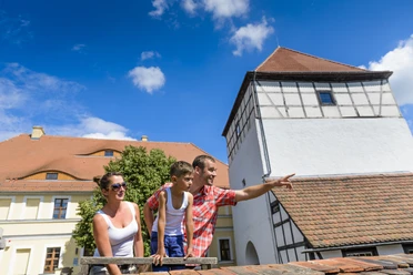 Burg Düben - Leipzig und Region mit Kindern Eine Familie mit Kind steht auf dem Gelände der Burg Düben im Sonnenschein und schaut sich die Umgebung an, Familie, Ausflug, Freizeit, Kultur