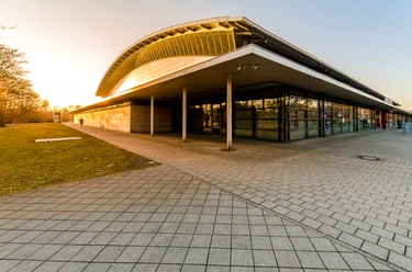 Vchod do QUARTERBACK Immobilien ARENA Leipzig ve večerním slunci, která slouží jako sportoviště, ale také jako jeviště a místo konání akcí, například koncertů.