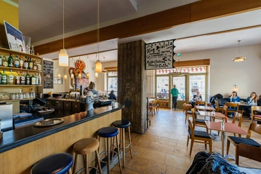 Café Cantona - Gastronomie Leipzig Blick in den gemütlichen Gastraum des Café Cantona mit Holzbar und breiter Fensterfront