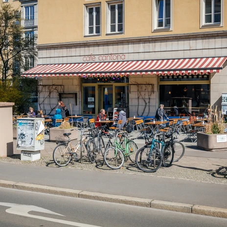 Widok na fasadę Café Cantona przy Windmühlenstraße z miejscami do siedzenia na zewnątrz i wieloma rowerami, gastronomia, kuchnia