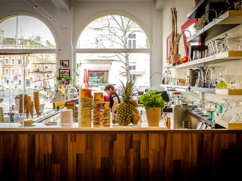 Eisträumerei Leipzig - Eisdielen & Cafés in Leipzig Foto aus dem Ladengeschäft mit Fokus auf den bunten Tresen, die Eisverkäuferin dahinter, die Schaufenster und den Blick auf die Straßenzüge im Hintergrund, cafe, eisdiele, freizeit