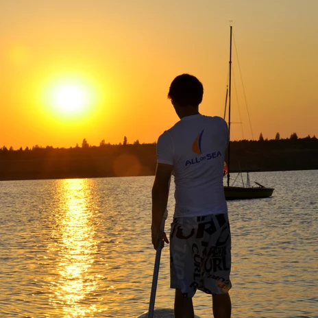 Ein junger Stand Up Paddler ist auf dem Schladitzer See bei Sonnenuntergang