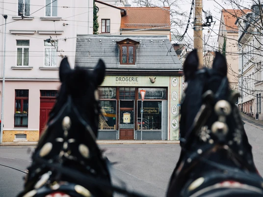 Drogerie - Gastronomie in Leipzig Blick auf die Außenfassade des Restaurant Drogerie in Leipzig mit Zugpferden und Tram im Vordergrund