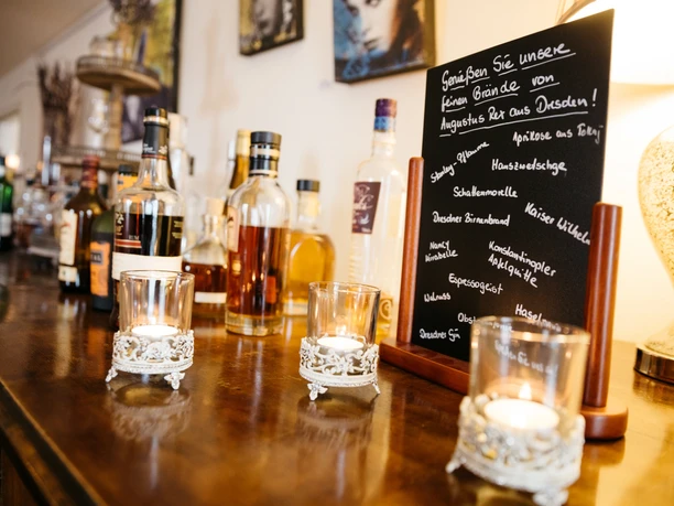 Droguerie - Gastronomie à Leipzig Vue sur le comptoir du restaurant Drogerie à Leipzig avec des spécialités actuelles, des bougies, des bouteilles et des photos