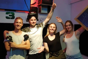 Čtyři usmívající se lidé ve virtuální únikové místnosti Escape Leipzig s brýlemi a ovladači.