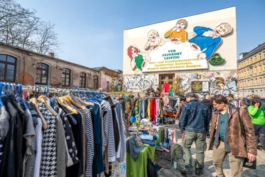 Flohmarkt auf der Feinkost Leipzig - Freizeiterlebnisse in Leipzig Flohmarkt mit vielen Besuchern vor der Leuchtreklame Löffelfamilie auf dem Gelände der Feinkost