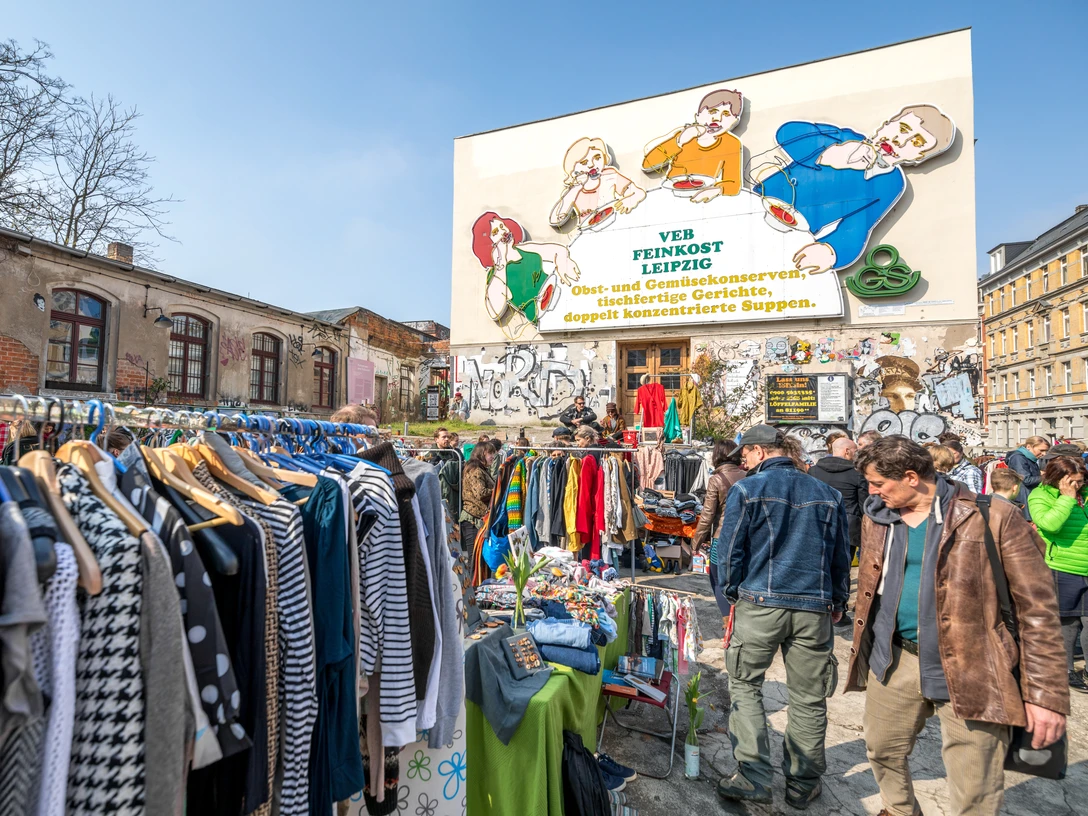 Flohmarkt auf der Feinkost Leipzig - Freizeiterlebnisse in Leipzig Flohmarkt mit vielen Besuchern vor der Leuchtreklame Löffelfamilie auf dem Gelände der Feinkost