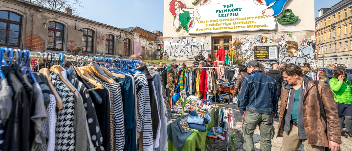 Flohmarkt auf der Feinkost Leipzig - Freizeiterlebnisse in Leipzig Flohmarkt mit vielen Besuchern vor der Leuchtreklame Löffelfamilie auf dem Gelände der Feinkost