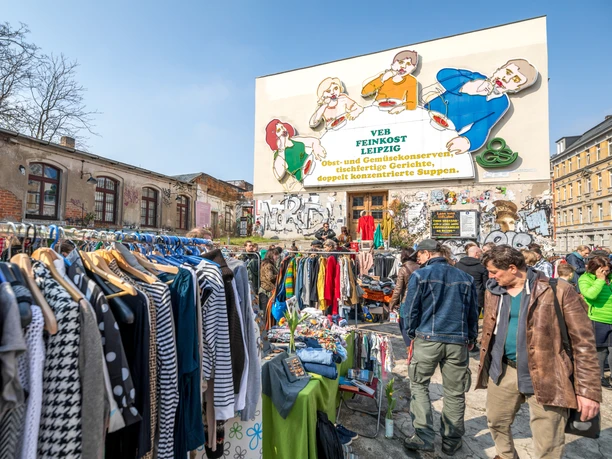 Flohmarkt auf der Feinkost Leipzig - Freizeiterlebnisse in Leipzig Flohmarkt mit vielen Besuchern vor der Leuchtreklame Löffelfamilie auf dem Gelände der Feinkost