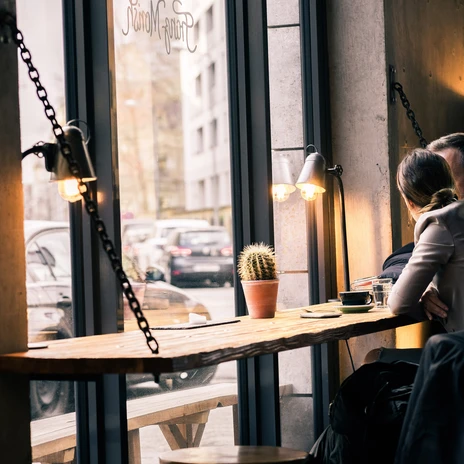 Photo de clients assis à l'une des fenêtres et regardant la rue en buvant un café ; ambiance, éclairage, café, culinaire