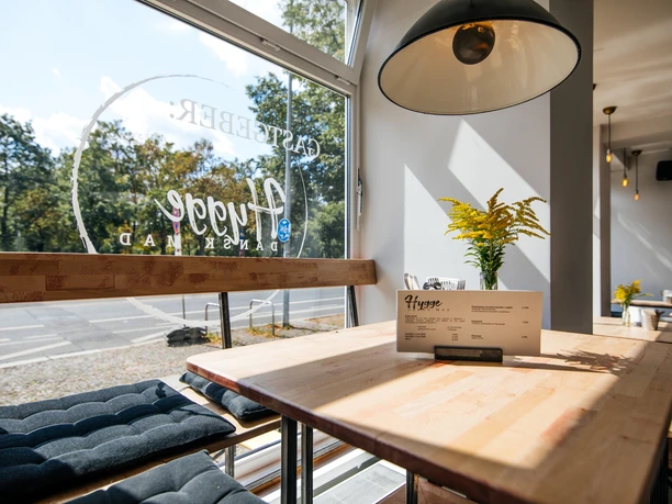 Fotografie eines Fensterplatzes im Gastgeber; Holztisch, Deko, Deckenlampe und Blick nach draußen, kulinarik, restaurant