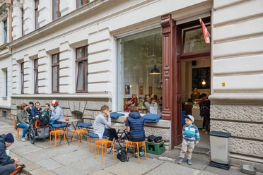 Gustav H. - Eisdielen & Eiscafés in Leipzig Blick auf die Fassade und den Freisitz des Gustav H., mit schlemmenden Gästen und spielenden Kindern, eisdiele, eiscafe, gastronomie