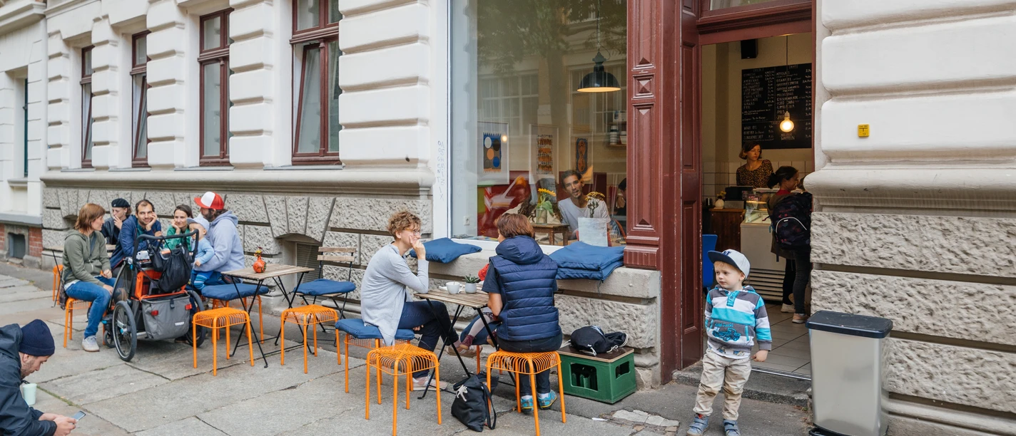 Gustav H. - Eisdielen & Eiscafés in Leipzig Blick auf die Fassade und den Freisitz des Gustav H., mit schlemmenden Gästen und spielenden Kindern, eisdiele, eiscafe, gastronomie