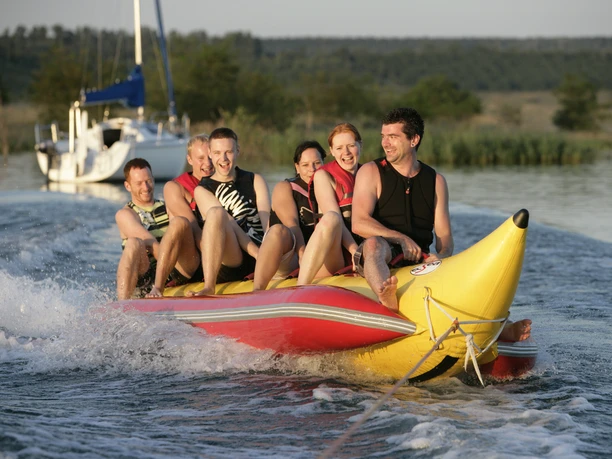 Young people sit on a banana boat on Lake Hain in Leipzig's Neuseenland.