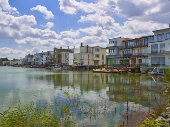 Lagune Kahnsdorf am Hainer See Moderne Wohnhäuser mit großen Fenstern und Balkonen spiegeln sich im ruhigen Wasser der Lagune Kahnsdorf.