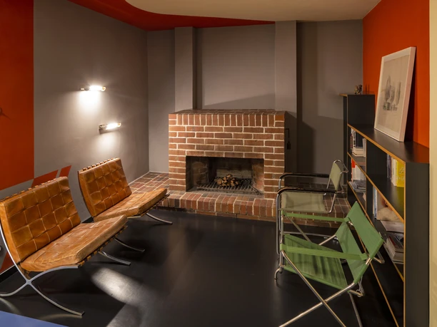 Centralnym punktem jest kominek w pokoju w Haus Rabe w Lipsku, który jest otoczony z lewej i prawej strony siedzeniami w stylu Bauhaus i ścianą półek