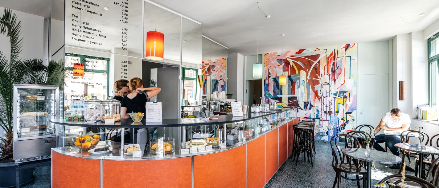 INO Café - Cafés in Leipzig Blick auf den Bar-Bereich des INO Cafés mit seiner Theke, der Bestuhlung und den Utensilien hinter der Bar, cafe, kaffeehaus, genuss, gastronomie