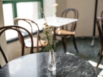 INO Café - Cafés in Leipzig Fotografie der Tischdeko im INO Café; Sträucher in Glasvase; im Hintergrund sind weitere Tische im hellen Café zu erkennen, Gastronomie, Cafe, freizeit