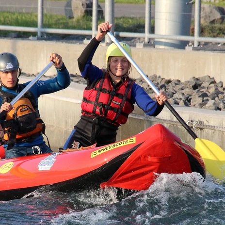 Dwie osoby siedzą w łodzi z kaskami i wiosłami podczas spływu DUO w Markkleeberg Canoe Park