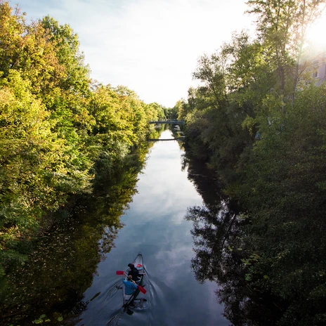 Zwei Kanufahrer in einem Kanu auf dem Karl-Heine-Kanal, umgeben von Bäumen, die sich langsam verfärben