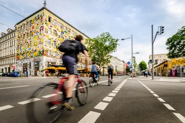 Rowerzysta jedzie wzdłuż modnej Karl-Liebknecht-Straße, znanej również jako Karli, która jest domem dla wielu barów i restauracji z miejscami do siedzenia na zewnątrz.