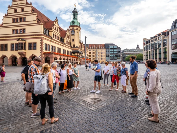 A group of people are standing at the market in Leipzig and are part of a city tour, city center, leisure time