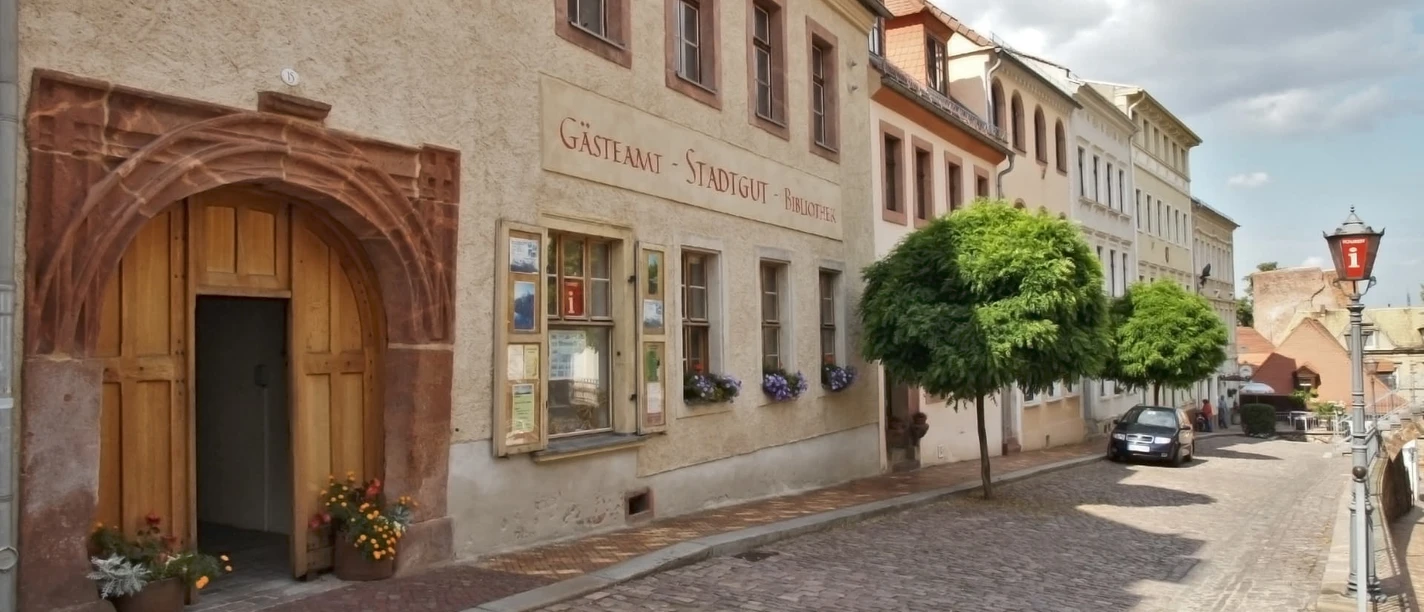 Gästeamt Leisnig im Stadtgut Das Bild zeigt die Aussenansicht des Stadtguts, die Fassade ist ockerfarben und es hat ein imposantes Tor.