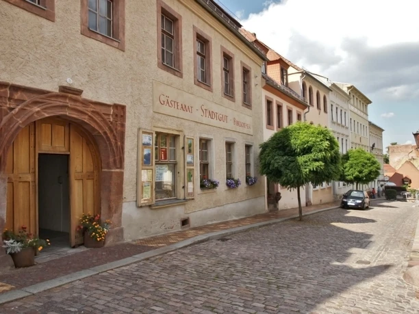 Gästeamt Leisnig im Stadtgut Das Bild zeigt die Aussenansicht des Stadtguts, die Fassade ist ockerfarben und es hat ein imposantes Tor.