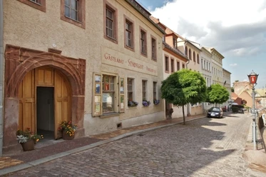 L'image montre l'extérieur du domaine municipal, la façade est de couleur ocre et il possède une porte imposante.