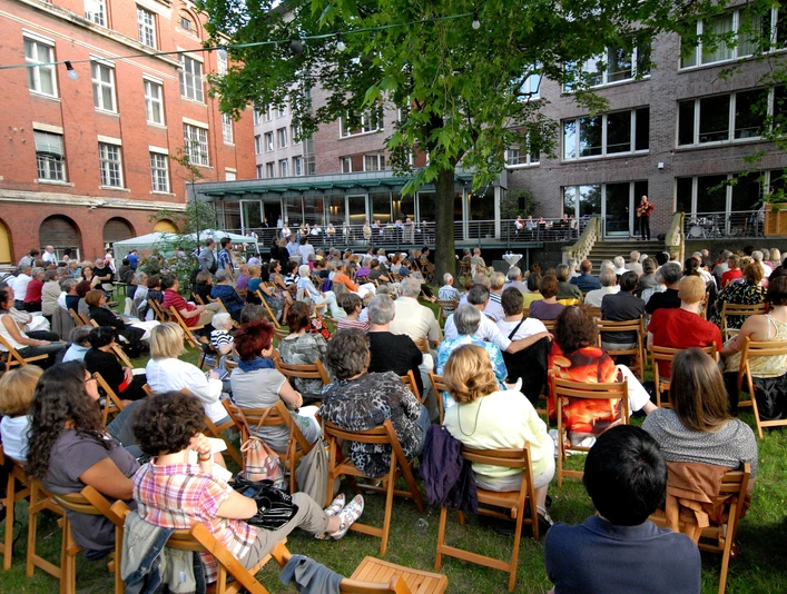 Haus des Buches - Moderne Architektur in Leipzig Der Innenhof des Haus des Buches ist beim Sommerfest des Literaturcafés voller Menschen, Veranstaltungen, Buchstadt, Kultureinrichtung, Architektur in Leipzig