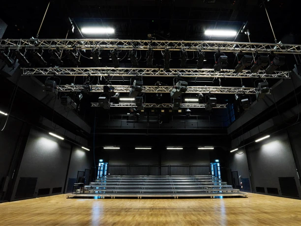 Vue de la scène du théâtre LOFFT sur les rangées de spectateurs dans une salle aux murs noirs avec éclairage, équipement culturel, loisirs