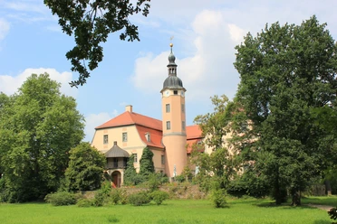 Schloss Machern im Schlosspark Das Schloss Machern erhebt sich prachtvoll inmitten üppiger Natur, mit seinen charakteristischen Türmen und einem gepflegten Garten davor.