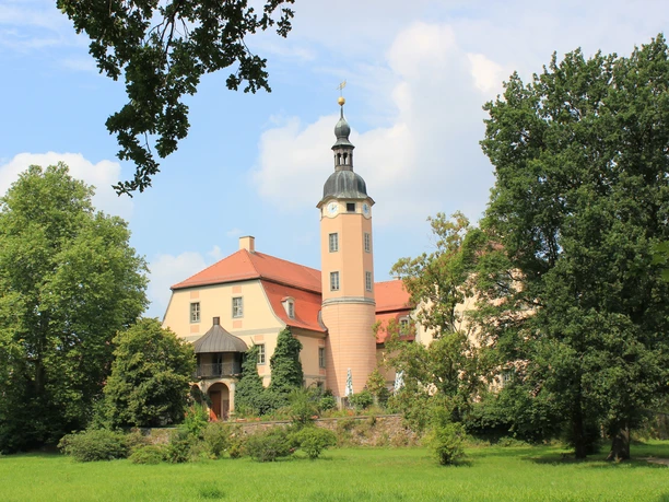 Schloss Machern im Schlosspark Das Schloss Machern erhebt sich prachtvoll inmitten üppiger Natur, mit seinen charakteristischen Türmen und einem gepflegten Garten davor.