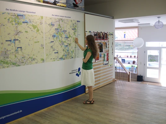Tourist-Information Leipziger Neuseenland in Markkleeberg - Besucherberatung und Service Eine Frau schaut sich die große Karte des Nördlichen und Südlichen Leipziger Neuseenlands in der Tourist-Information Leipziger Neuseenlands in Markkleeberg an, Leipzig Region