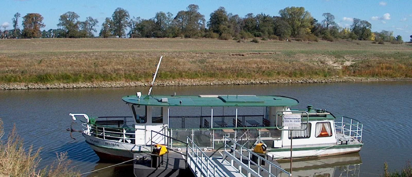 Motorboot Roland Ein grünes Motorboot mit Rampe liegt friedlich am Flussufer vor Anker.