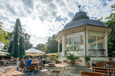 Musikpavillon - Gastronomie in Leipzig Fotografie des Freisitzes und schönen weißen Pavillons an einem Sommertag im Clara-Zetkin-Park; mit Bewaldung im Hintergrund, Sonnenschirmen