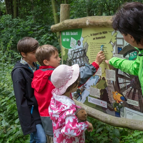 Eine Gruppe von Kindern steht vor einer Infotafel auf der Heide-Biber-Tour mit Billi Bockert, Biber aus der Heide