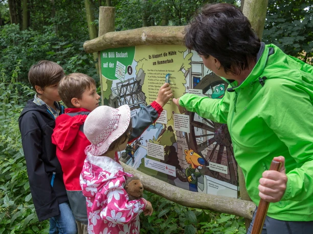 Mit Billi Bockert auf der Heide-Biber-Tour - Leipzig und Region Eine Gruppe von Kindern steht vor einer Infotafel auf der Heide-Biber-Tour mit Billi Bockert, Biber aus der Heide