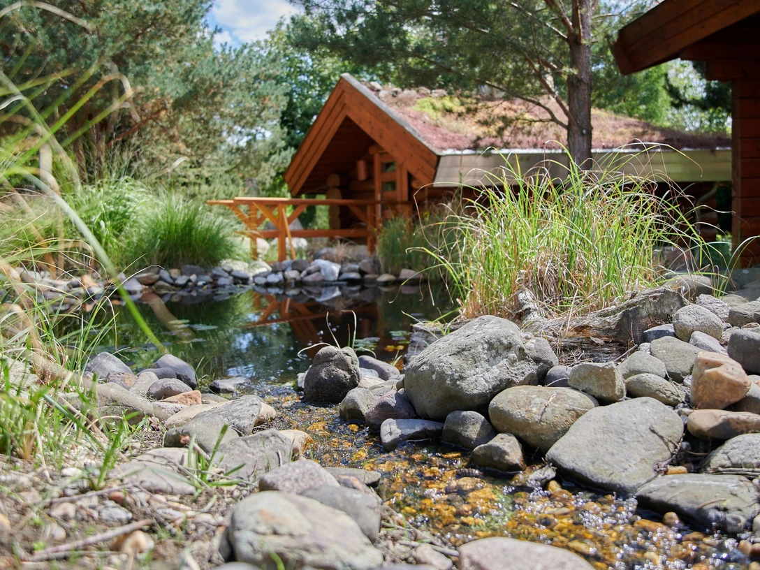 Saunadorf Oschatz - Wellness in der Leipzig Region Blick auf das Saunadorf mit kleinen Holzhütten an einem Bach in Oschatz gelegen